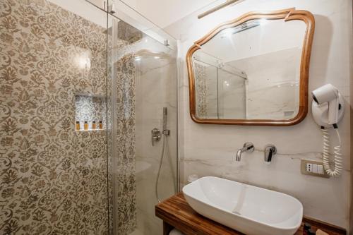 a bathroom with a shower and a sink and a mirror at Palazzo Giunta - Porta Marina Ortigia in Siracusa