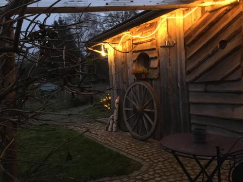 a wooden cabin with a wheel outside at night at Gîtanneke in Burg-Reuland