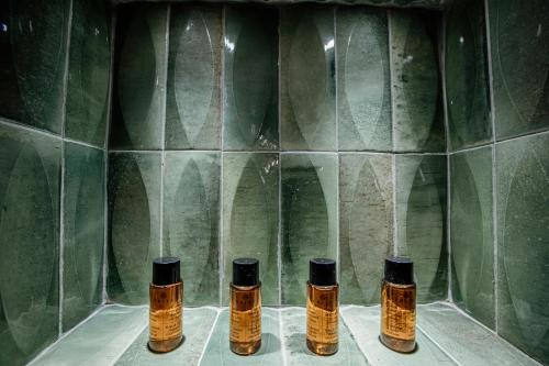 a group of four bottles in a shower with green tiles at Palazzo Giunta - Porta Marina Ortigia in Siracusa