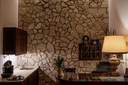 a stone wall in a kitchen with a table and a lamp at Palazzo Giunta - Porta Marina Ortigia in Siracusa