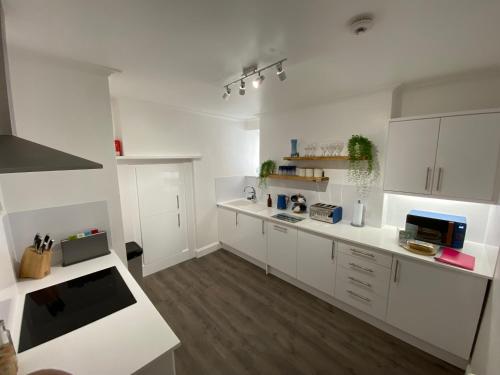 a large white kitchen with white cabinets and wooden floors at Bank Place in Falmouth