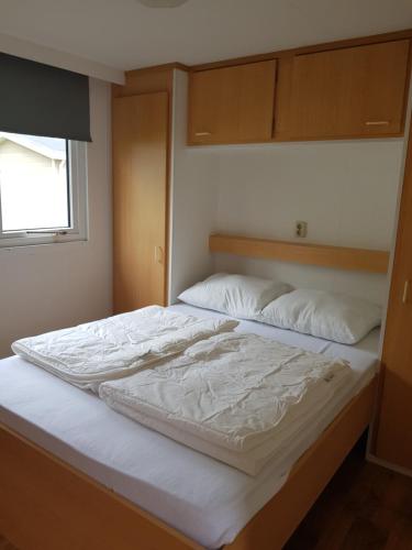 een groot wit bed in een kamer met een raam bij De Bijsselse Enk, Lelie in Nunspeet