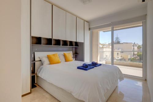 um quarto com uma cama branca e uma grande janela em Cosy 1BR Apartment in central St Julian's em St. Julian's