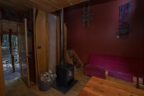 a living room with a red couch and a wood stove at Cabañas Ensenada Bosque Nativo in Ensenada