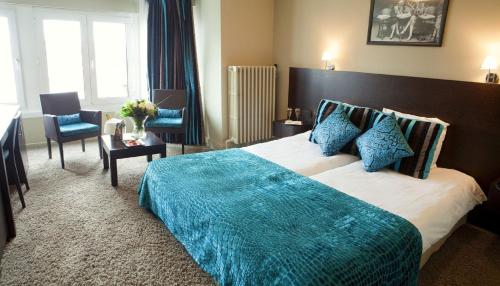 a bedroom with a large bed with a blue blanket at The Memlinc in Knokke-Heist