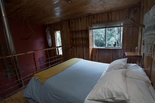a bedroom with a white bed in a wooden room at Cabañas Ensenada Bosque Nativo in Ensenada