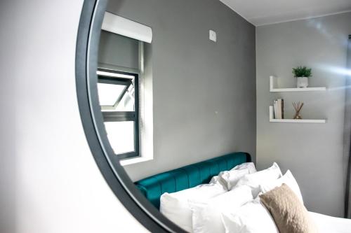 um reflexo de espelho de uma cama num quarto em “Pop Inn” modern apartment in heart of Bryanston em Joanesburgo