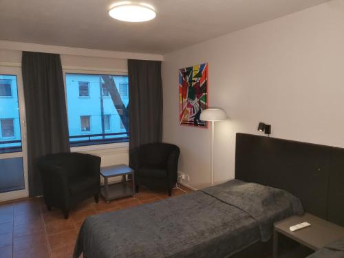 um quarto com uma cama, 2 cadeiras e uma janela em Hotel Esplanad em Mariehamn