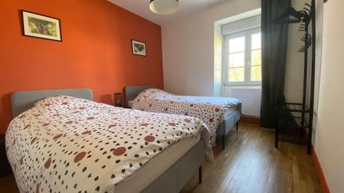 2 camas en una habitación con paredes de color naranja en Le gîte de l’espérance en Arc-en-Barrois