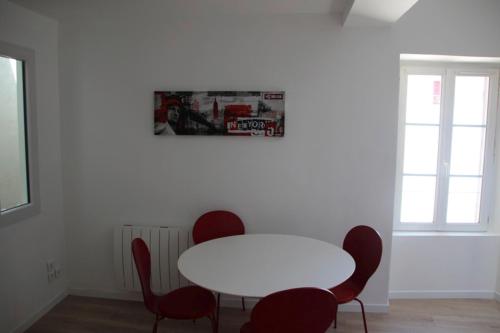 een witte tafel en stoelen in een kamer met een witte tafel en rode stoelen bij 40m All Comfort In Front Of The Old Port in La Rochelle