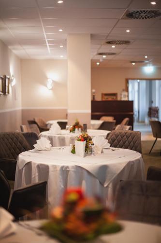 a dining room with tables and chairs with flowers on them at Waldhotel Eiche in Burg