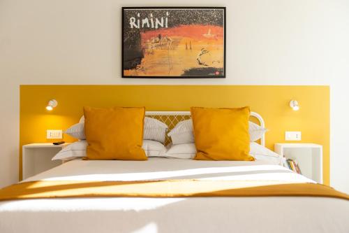 Corso51 Suite Apartments في ريميني: غرفة نوم بسرير كبير مع مخدات صفراء