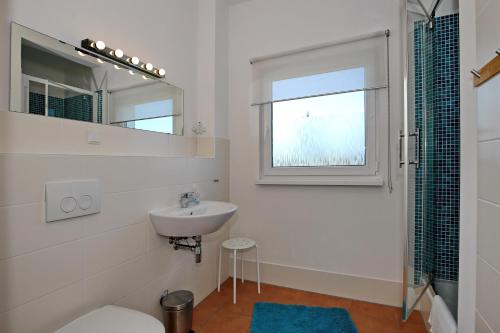 a white bathroom with a sink and a mirror at Macoma Baltica Wohnung 04 in Kühlungsborn