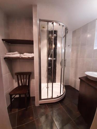 La salle de bains est pourvue d'une douche, d'une chaise et d'un lavabo. dans l'établissement Logis Hôtel Restaurant L'Auberge du Chateau, à Muret-le-Château