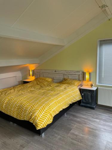 a bedroom with a yellow bed and two lamps at Onder de pannen in Stavoren