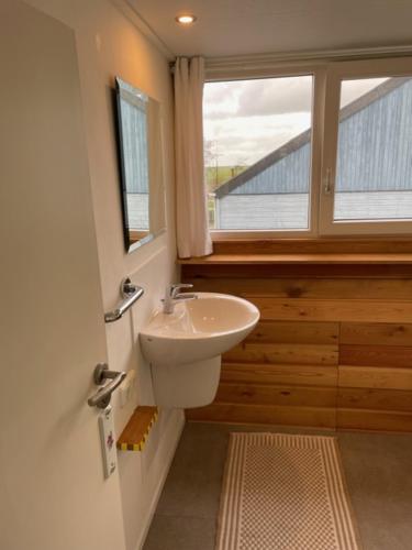 ein Bad mit einem Waschbecken und einem Fenster in der Unterkunft Onder de pannen in Stavoren