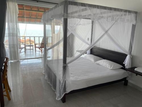 1 dormitorio con cama con dosel y vistas al océano en ISAMAR FRONT BEACH, en Marawila