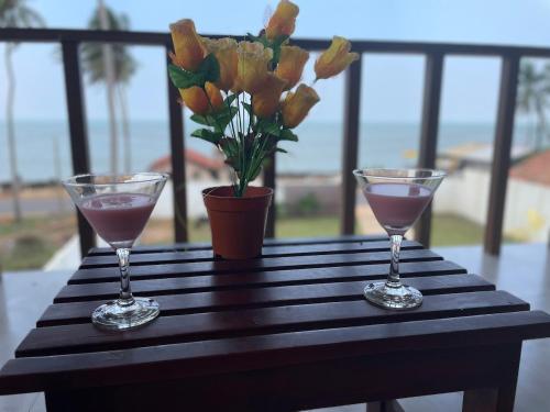 dos copas de vino en una mesa con un jarrón de flores en ISAMAR FRONT BEACH, en Marawila