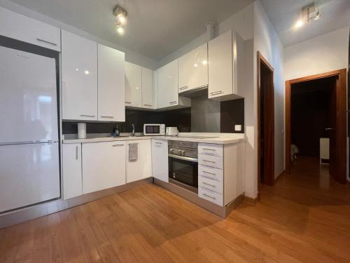 a kitchen with white cabinets and a wooden floor at Palacio Santa Ursula in Toledo