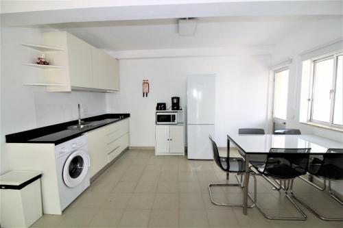 a white kitchen with a table and a washing machine at Historic Centre B - Albufeira in Albufeira