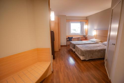 a hotel room with two beds and a desk at Zago Hotel in Lages