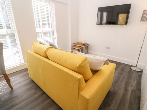 a yellow couch in a living room with a television at Perran Pearl A in Perranporth