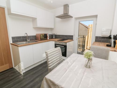 a kitchen with a table with a vase of flowers on it at Perran Pearl A in Perranporth