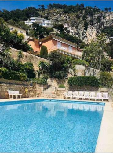 une grande piscine avec des chaises et une maison dans l'établissement Villefranche Sur Mer:Appartement-villa, Vue mer, jardin, parking., à Villefranche-sur-Mer