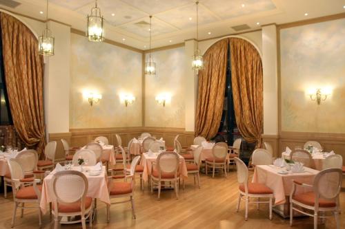 a dining room with tables and chairs and chandeliers at Volos Palace in Volos