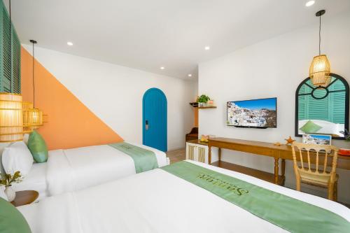 a hotel room with two beds and a desk at Santori Hotel And Spa in Da Nang