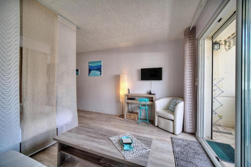 a living room with a table and a chair and a television at IMMOGROOM - Near the city centre and the beach - Air conditioning - Terrace in Cannes