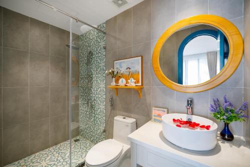 a bathroom with a sink and a toilet and a mirror at Santori Hotel And Spa in Da Nang