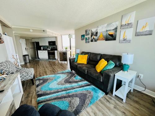 a living room with a black leather couch and a rug at 1602 Coastal Soul Pet friendly in Myrtle Beach