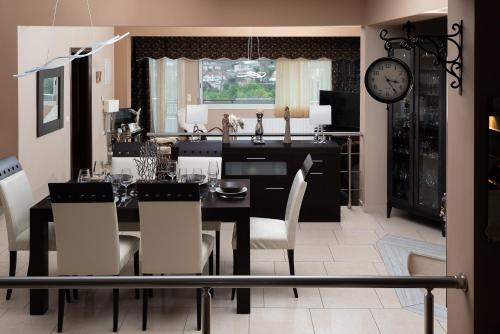 a dining room with a table and chairs and a clock at Villa Kalaitsidi - plunge pool, gym and unique gardens in Skinés
