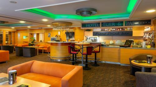 a restaurant with orange chairs and a bar at Hotel Eger & Park in Eger