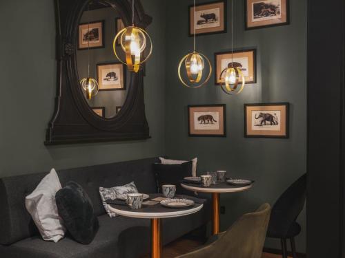a living room with a couch and two tables and a mirror at Maisons du Monde Hotel & Suites - Nantes in Nantes