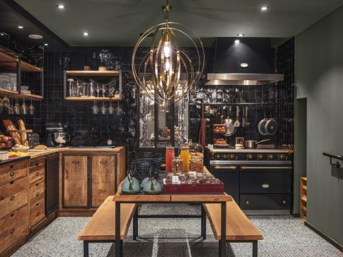 a kitchen with a table and a chandelier at Maisons du Monde Hotel & Suites - Nantes in Nantes
