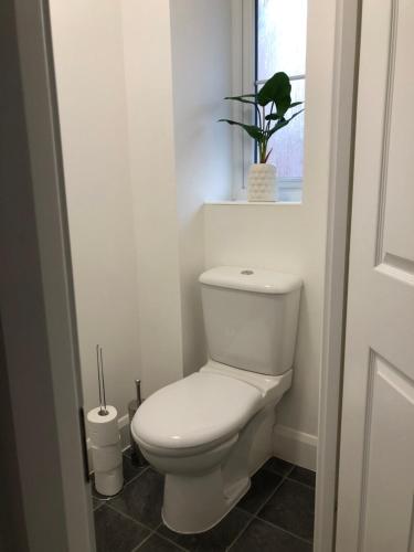 a white toilet in a bathroom with a window at Hill House - 5 Mins Merry Hill - Perfect for Contractors & Families in Brettell Lane