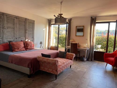 Schlafzimmer mit einem Bett, einem Stuhl und Fenstern in der Unterkunft Côté Dentelles in Vacqueyras