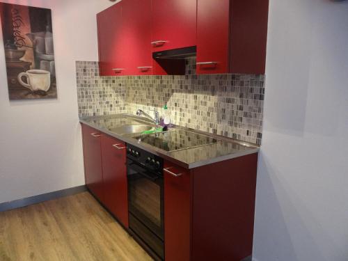 a kitchen with red cabinets and a sink at Apartment nearby Titlis Station in Engelberg