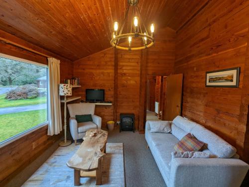 una sala de estar con sofá y mesa en una cabaña en Ruskin Lodges Argyll, by Puck's Glen, Rashfield near Dunoon en Dunoon