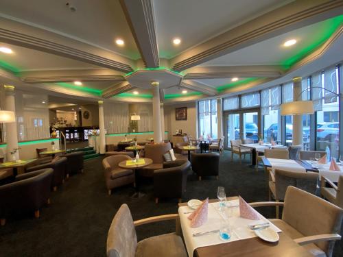 un restaurante con mesas, sillas y luces verdes en Hotel Am Schloss Aurich, en Aurich