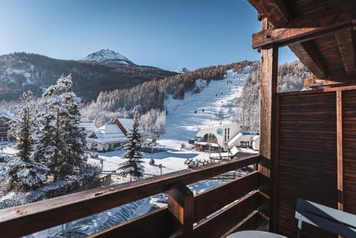 una vista da un balcone di una stazione sciistica nella neve di Grand Hôtel & Spa NUXE Serre Chevalier a Saint-Chaffrey