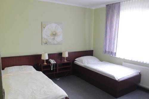 ゼーセンにあるLandhaus Zum alten Fritzのベッドルーム1室(ベッド2台付)、花の写真が飾られた窓が備わります。