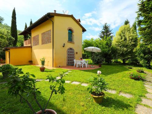 uma pequena casa amarela com uma mesa num quintal em Holiday Home Il Masso-4 by Interhome em La Collina