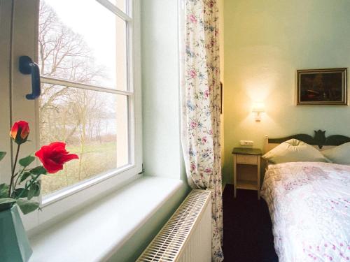 a bedroom with a window with a flower on the sill at Landhotel Schloss Daschow in Daschow