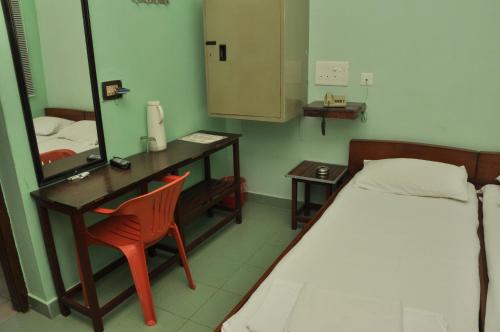 een slaapkamer met een bed, een bureau en een spiegel bij VALLI HOTEL in Thanjāvūr
