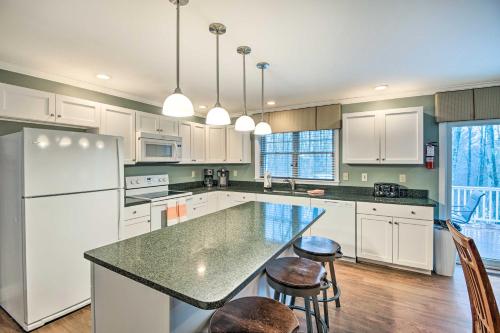 a kitchen with white cabinets and a large island with stools at North Conway Home about 2 Mi to Cranmore Mountain! in North Conway