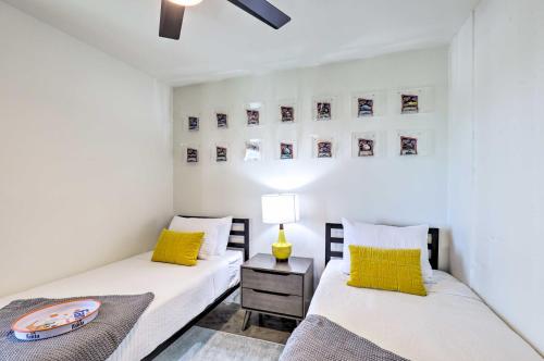 two beds in a room with white walls and yellow pillows at Unique Texas Home in Converted Gas Station! in Schulenburg