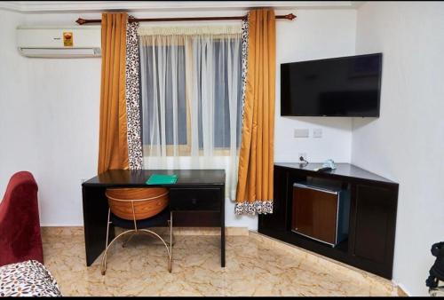 Cette chambre comprend un bureau avec une télévision et une chaise. dans l'établissement ROYAL BASIN RESORT, à Kumasi